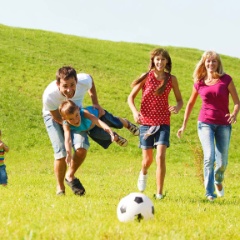 Familie am Fussball spielen auf dem Rasen